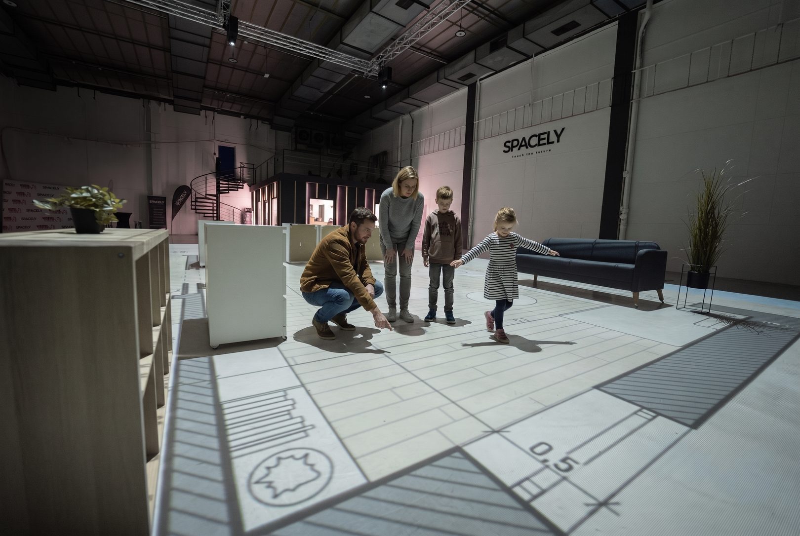 Rodina si prochází půdorys svého budoucího domu promítnutý v životní velikosti na podlaze haly Spacely